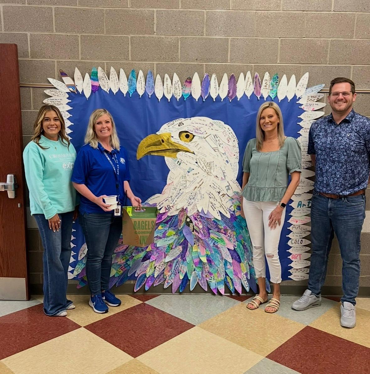 Columbia school supporters standing beside student eagle artwork